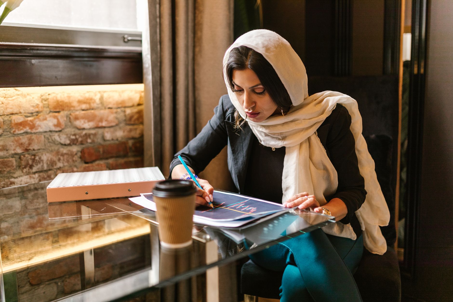 entrepreneur reviewing marketing guidebook at coffee table with digital tablet